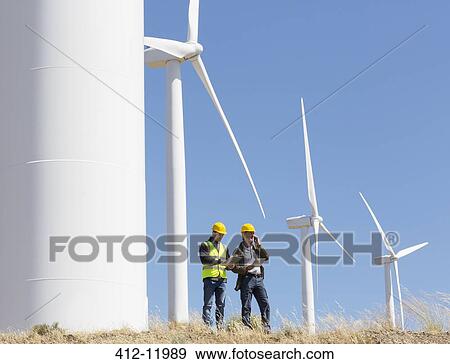 Workers talking by wind turbines in rural landscape View Large Photo Image Stock Photo - Workers talking by wind turbines in rural landscape. Fotosearch