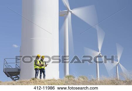 Workers talking by wind turbines in rural landscape View Large Photo Image Stock Photograph - Workers talking by wind turbines in rural landscape. Fotosearch