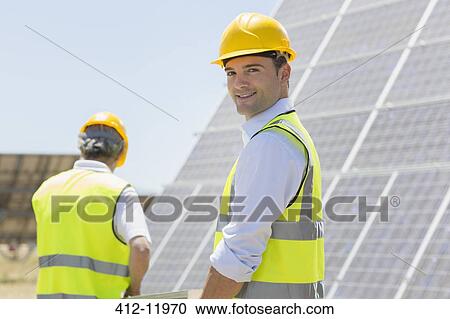 Workers walking by solar panels in rural landscape View Large Photo Image Stock Image - Workers walking by solar panels in rural landscape. Fotosearch