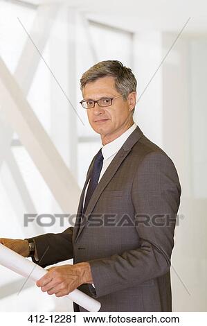 Architect holding blueprints in office View Large Photo Image Stock Image - Architect holding blueprints in office. Fotosearch