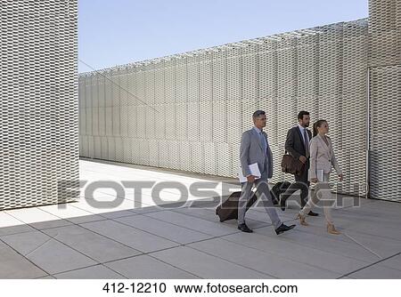 Stock Image - Business people walking with suitcases outdoors. Fotosearch