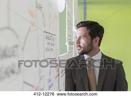 Stock Photograph - Businessman looking out hole in office window. Fotosearch