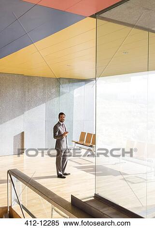 Stock Photography - Businessman smiling in sunny office lobby. Fotosearch
