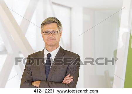 Businessman standing in office View Large Photo Image Stock Image - Businessman standing in office. Fotosearch