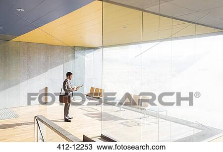 Businessman standing in sunny office lobby View Large Photo Image Stock Image - Businessman standing in sunny office lobby. Fotosearch