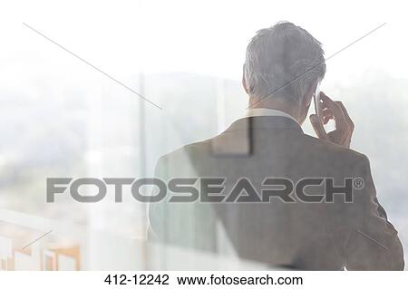 Businessman talking on cell phone in office View Large Photo Image Stock Image - Businessman talking on cell phone in office. Fotosearch