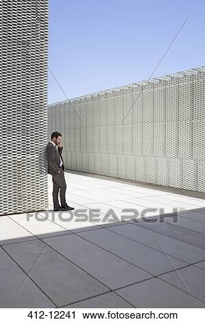 Stock Image - Businessman talking on cell phone outdoors. Fotosearch