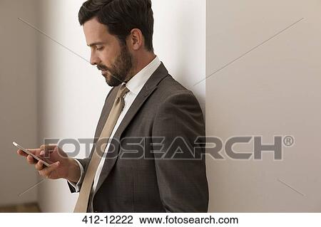 Stock Image - Businessman using cell phone in office. Fotosearch