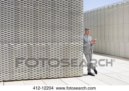 Businessman using cell phone outdoors View Large Photo Image Picture - Businessman using cell phone outdoors. Fotosearch