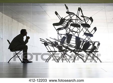 Stock Image - Businessman viewing office chair installation art. Fotosearch