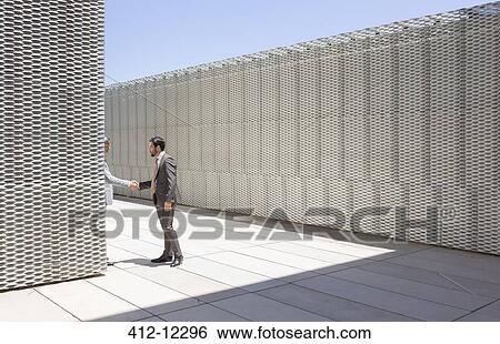 Stock Photograph - Businessmen shaking hands outdoors. Fotosearch