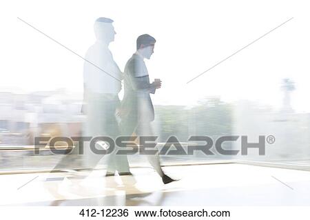 Stock Photograph - Businessmen walking in sunny airport corridor. Fotosearch