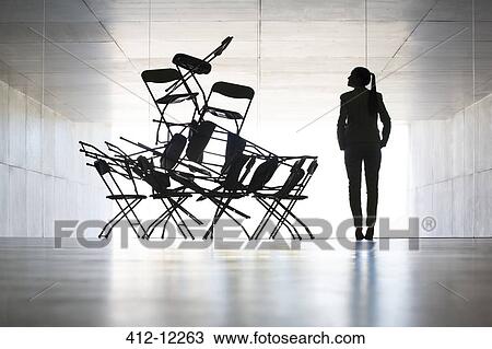 Stock Image - Businesswoman examining office chair installation art. Fotosearch