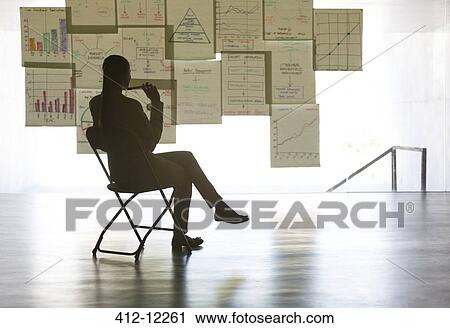 Businesswoman studying charts and graphs on wall in office View Large Photo Image Stock Image - Businesswoman studying charts and graphs on wall in office. Fotosearch