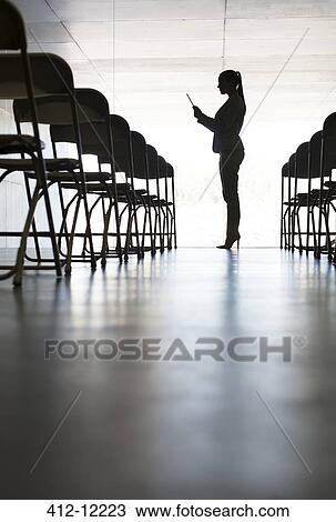 Stock Image - Silhouette of businesswoman with digital tablet in office. Fotosearch