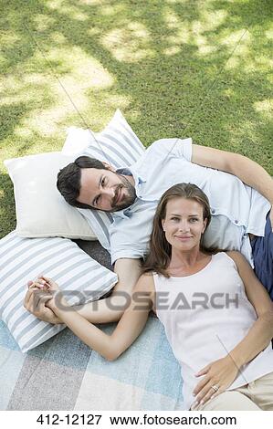 Couple relaxing on picnic blanket View Large Photo Image Stock Photo - Couple relaxing on picnic blanket. Fotosearch
