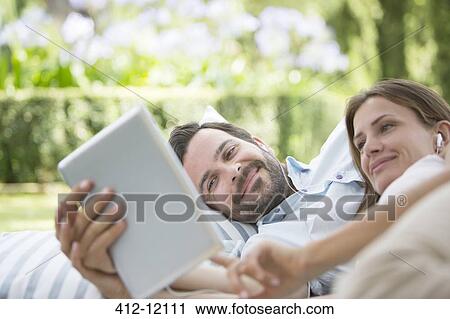 Couple using digital tablet outdoors View Large Photo Image Stock Image - Couple using digital tablet outdoors. Fotosearch