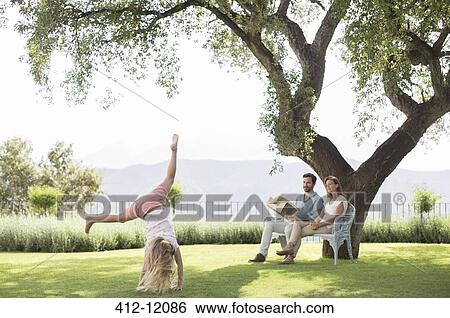 Couple watching daughter do cartwheel outdoors View Large Photo Image Stock Photograph - Couple watching daughter do cartwheel outdoors. Fotosearch