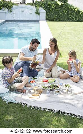 Stock Image - Family enjoying picnic in backyard. Fotosearch