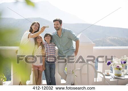 Stock Image - Family taking self-portrait on sunny balcony. Fotosearch