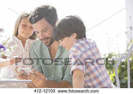 Father and children using cell phone outdoors View Large Photo Image Stock Image - Father and children using cell phone outdoors. Fotosearch