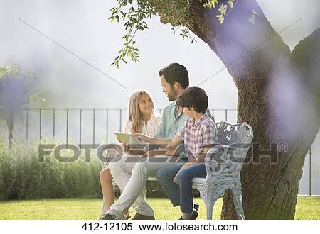 Father and children using digital tablet on bench in park View Large Photo Image Stock Photography - Father and children using digital tablet on bench in park. Fotosearch