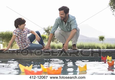 Father and son watching origami boats in swimming pool View Large Photo Image Stock Photo - Father and son watching origami boats in swimming pool. Fotosearch
