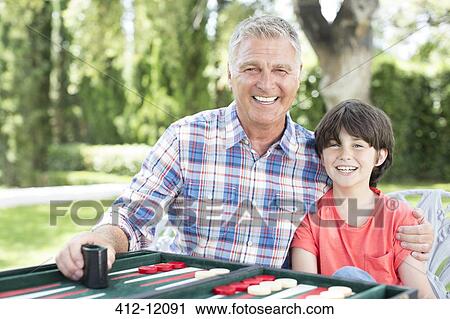 Grandfather and grandson playing backgammon on patio View Large Photo Image Stock Image - Grandfather and grandson playing backgammon on patio. Fotosearch