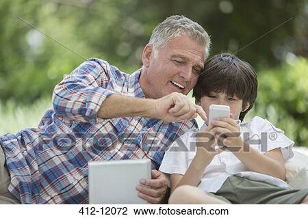 Grandfather and grandson using digital tablet and cell phone View Large Photo Image Stock Image - Grandfather and grandson using digital tablet and cell phone. Fotosearch