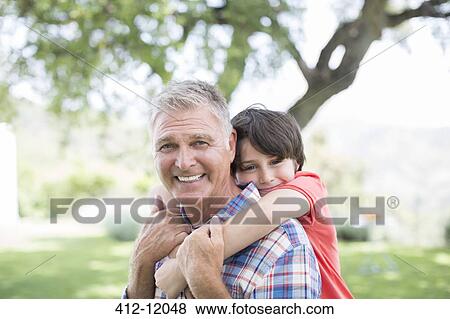 Man piggybacking grandson outdoors View Large Photo Image Stock Photo - Man piggybacking grandson outdoors. Fotosearch