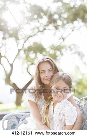 Stock Image - Mother and daughter hugging outdoors. Fotosearch
