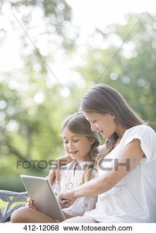 Mother and daughter using digital tablet outdoors View Large Photo Image Stock Photo - Mother and daughter using digital tablet outdoors. Fotosearch