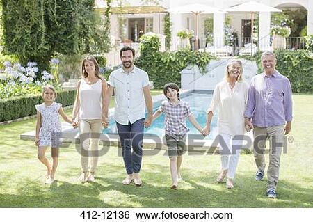 Stock Photograph - Multi-generation family holding hands and walking in backyard. Fotosearch