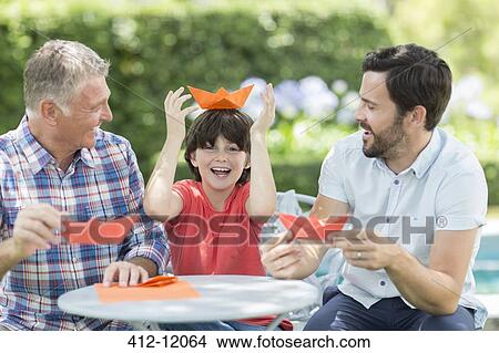 Multi-generation men making origami hats outdoors View Large Photo Image Picture - Multi-generation men making origami hats outdoors. Fotosearch