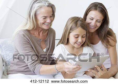 Stock Image - Multi-generation women using digital tablet. Fotosearch