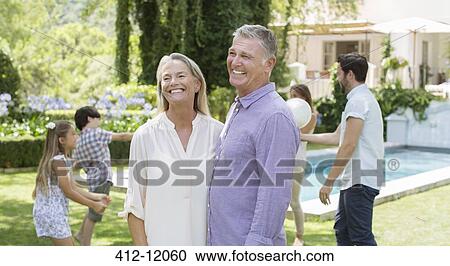 Stock Image - Senior couple in backyard with family. Fotosearch