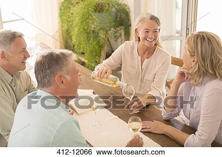 Senior couples drinking wine at dining table View Large Photo Image Stock Photograph - Senior couples drinking wine at dining table. Fotosearch
