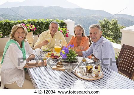 Senior couples enjoying breakfast on patio View Large Photo Image Picture - Senior couples enjoying breakfast on patio. Fotosearch