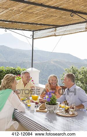 Senior couples enjoying breakfast on balcony overlooking mountains View Large Photo Image Picture - Senior couples enjoying breakfast on balcony overlooking mountains. Fotosearch