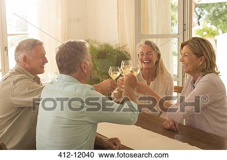 Senior couples toasting wine glasses at table View Large Photo Image Stock Image - Senior couples toasting wine glasses at table. Fotosearch