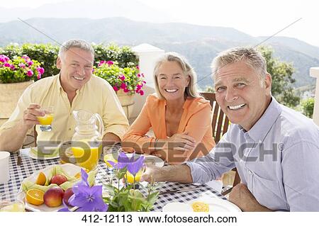 Senior friends enjoying breakfast on balcony View Large Photo Image Stock Image - Senior friends enjoying breakfast on balcony. Fotosearch