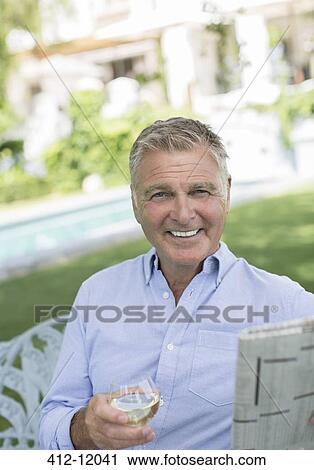 Senior man reading newspaper and drinking wine in backyard View Large Photo Image Stock Image - Senior man reading newspaper and drinking wine in backyard. Fotosearch