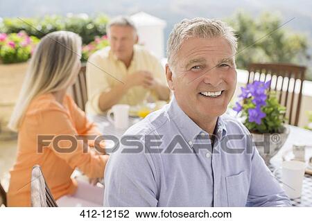 Senior man smiling at patio table View Large Photo Image Stock Image - Senior man smiling at patio table. Fotosearch