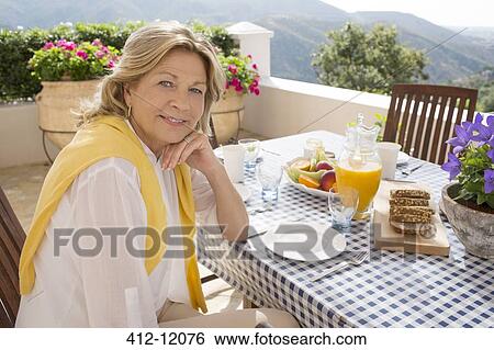 Senior woman eating breakfast at table on balcony View Large Photo Image Stock Photograph - Senior woman eating breakfast at table on balcony. Fotosearch