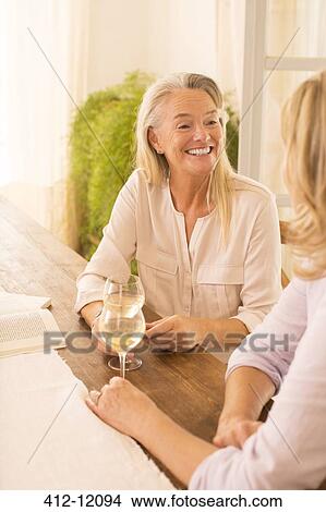 Senior women drinking white wine at dining table View Large Photo Image Picture - Senior women drinking white wine at dining table. Fotosearch