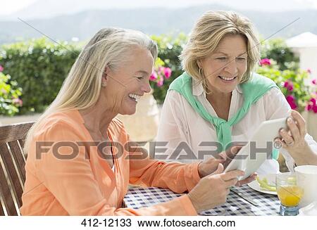 Senior women using digital tablet at patio table View Large Photo Image Stock Image - Senior women using digital tablet at patio table. Fotosearch