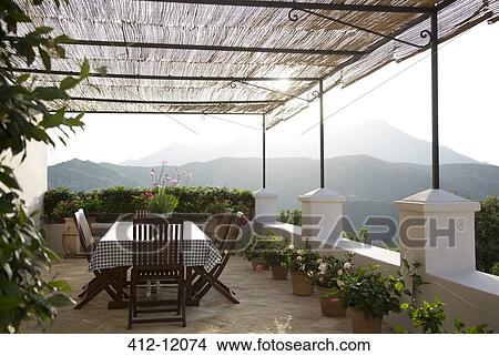 Picture - Table and chairs on balcony overlooking mountains. Fotosearch