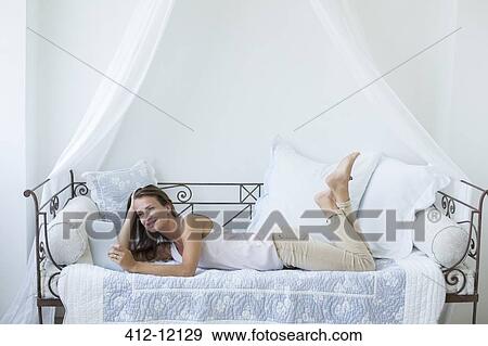 Woman using digital tablet on daybed View Large Photo Image Stock Photo - Woman using digital tablet on daybed. Fotosearch