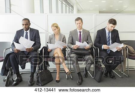 Stock Image - Business people reading in waiting area. Fotosearch