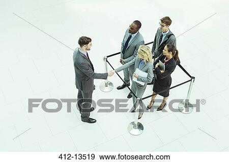 Stock Photo - Business people shaking hands in waiting area. Fotosearch